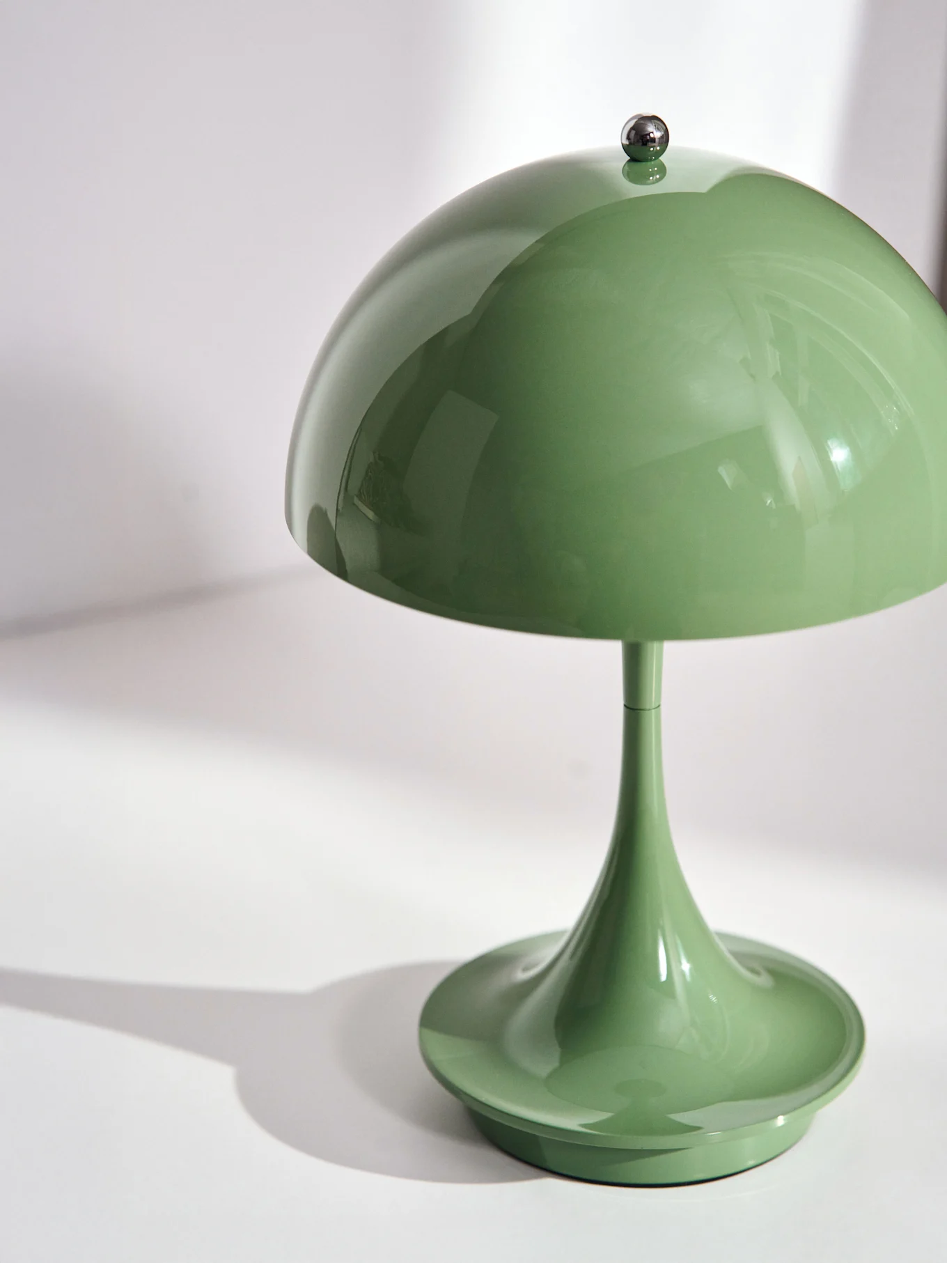 Glossy green mushroom table lamp on a white surface.