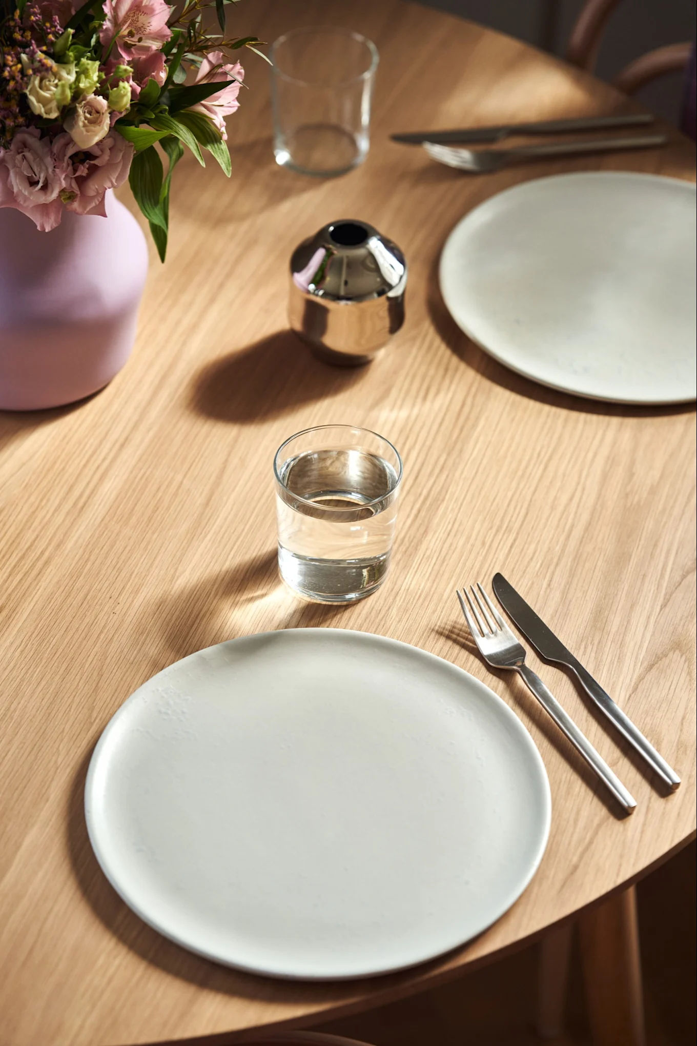 An overhead shot of a place setting with a simple white plate and the lilac Dorotea vase for Gense.