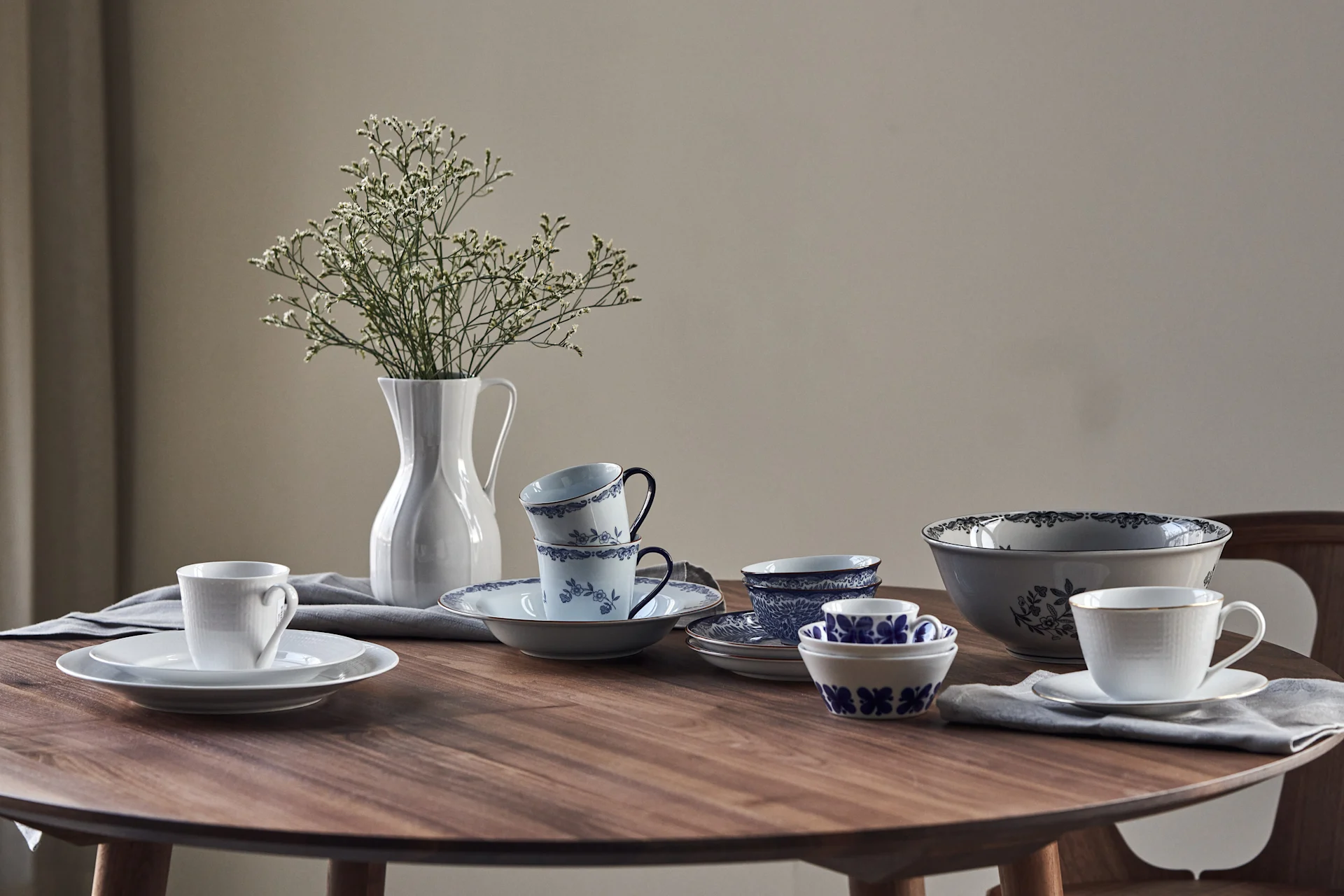 Rörstrand's porcelain classics are lined up on a round table: Mon Amie, Swedish Grace, Ostindia in blue and black and the Pli Blanc jug.