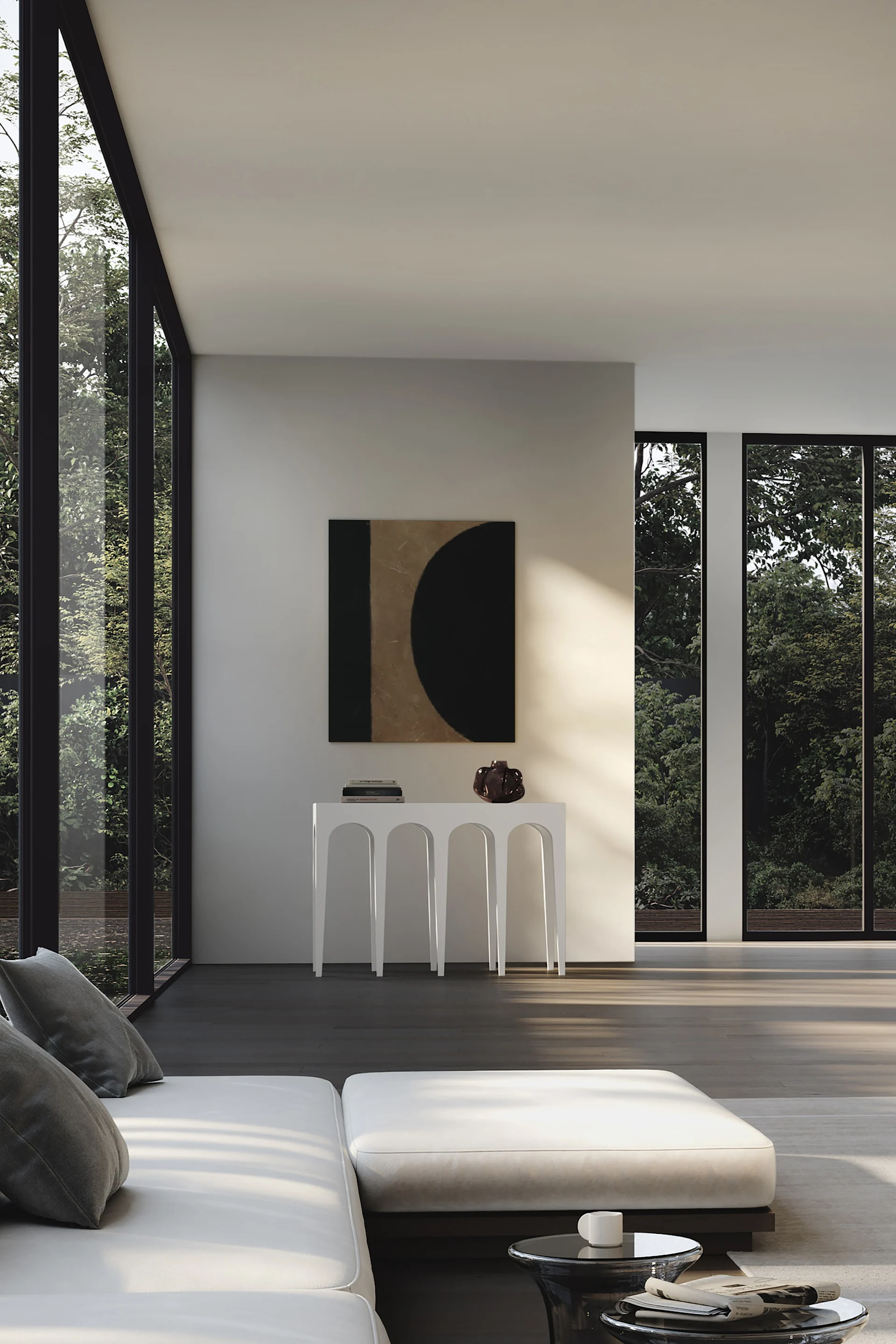 A modern living room with a white sofa, a console table under an abstract painting, and large windows revealing green trees.