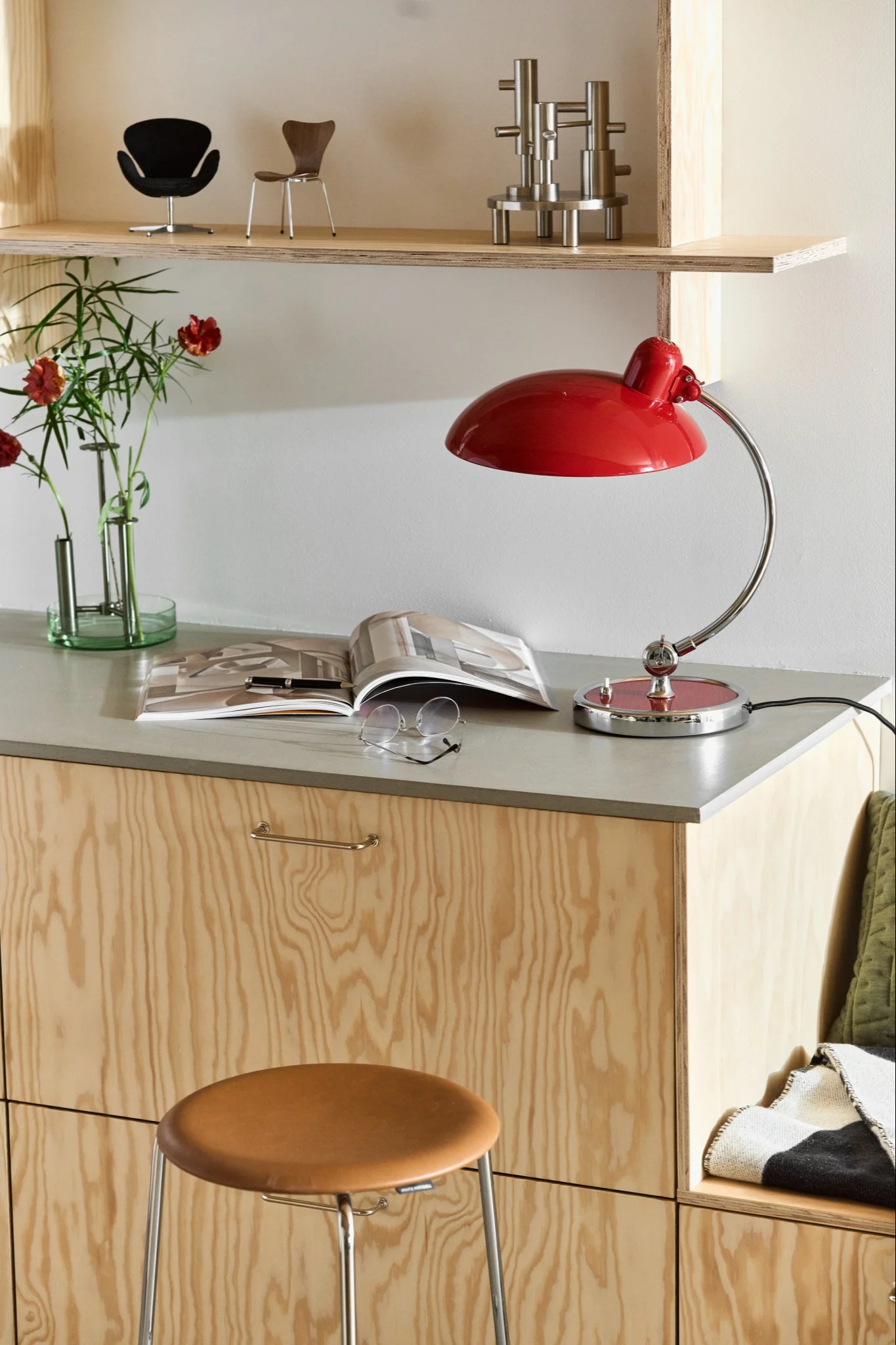 Here you see a number of Fritz Hansen products in a reading nook in a modern kitchen. You see the Kaiser lamp in ruby red and the dot stool in leather.