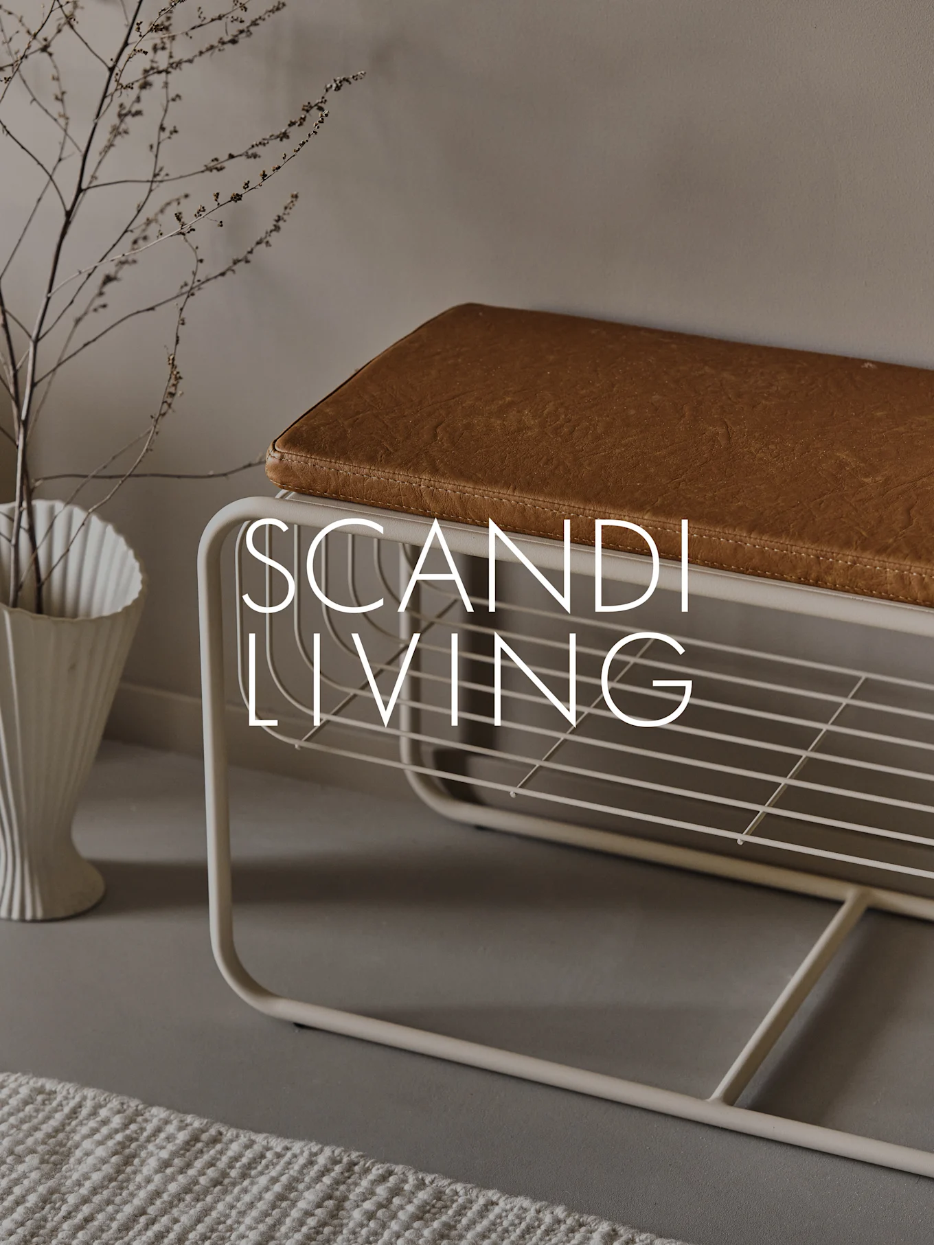 Entryway bench with a brown cushion, shoe shelf, white fluted vase with branches, and text 'SCANDI LIVING'.
