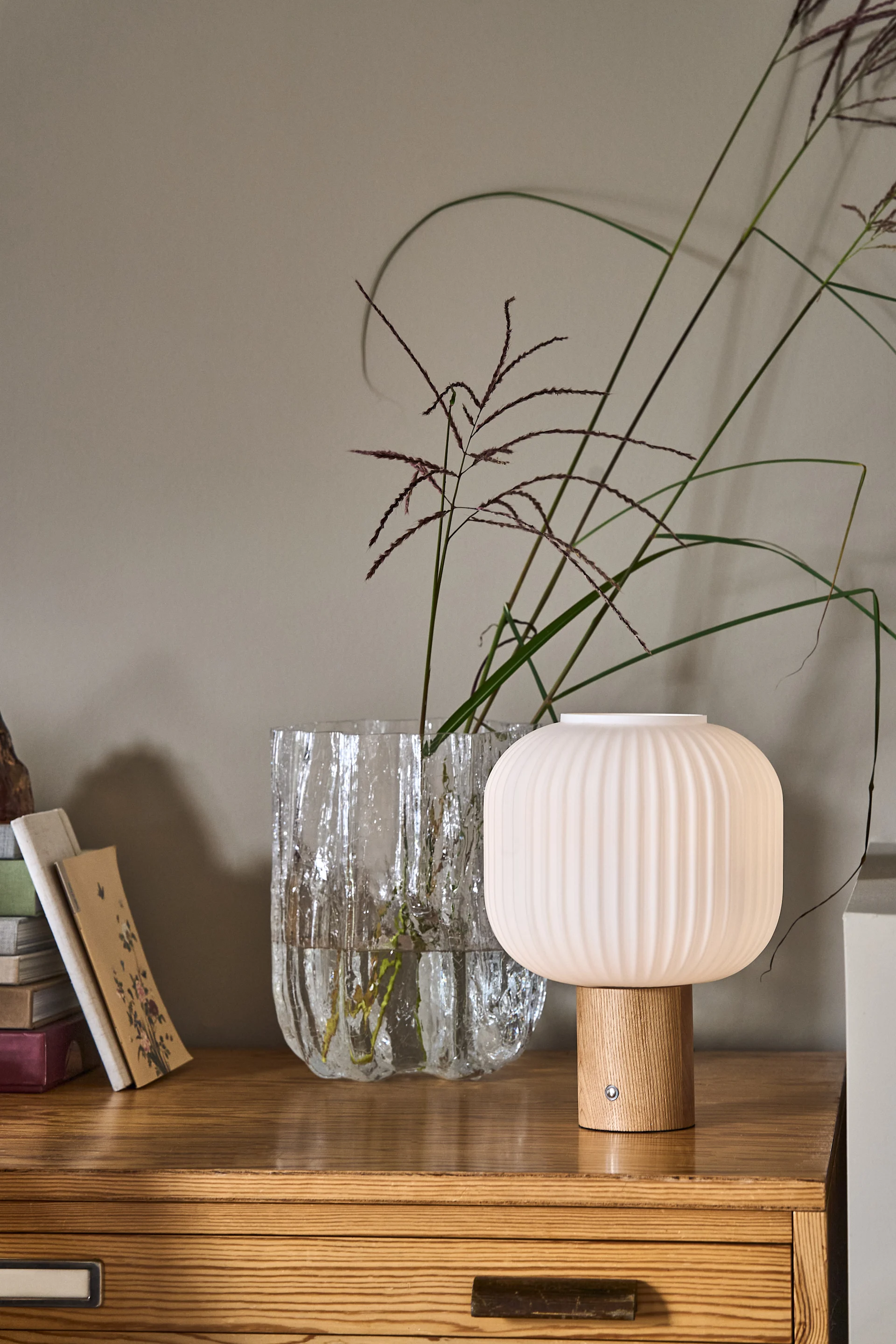 At @oursmall.home you can see two possible Mother's Day gifts: the Pantorp table lamp from Verpan stands on a chest of drawers, next to it the Crumple vase from Byon with a few twigs in it.
