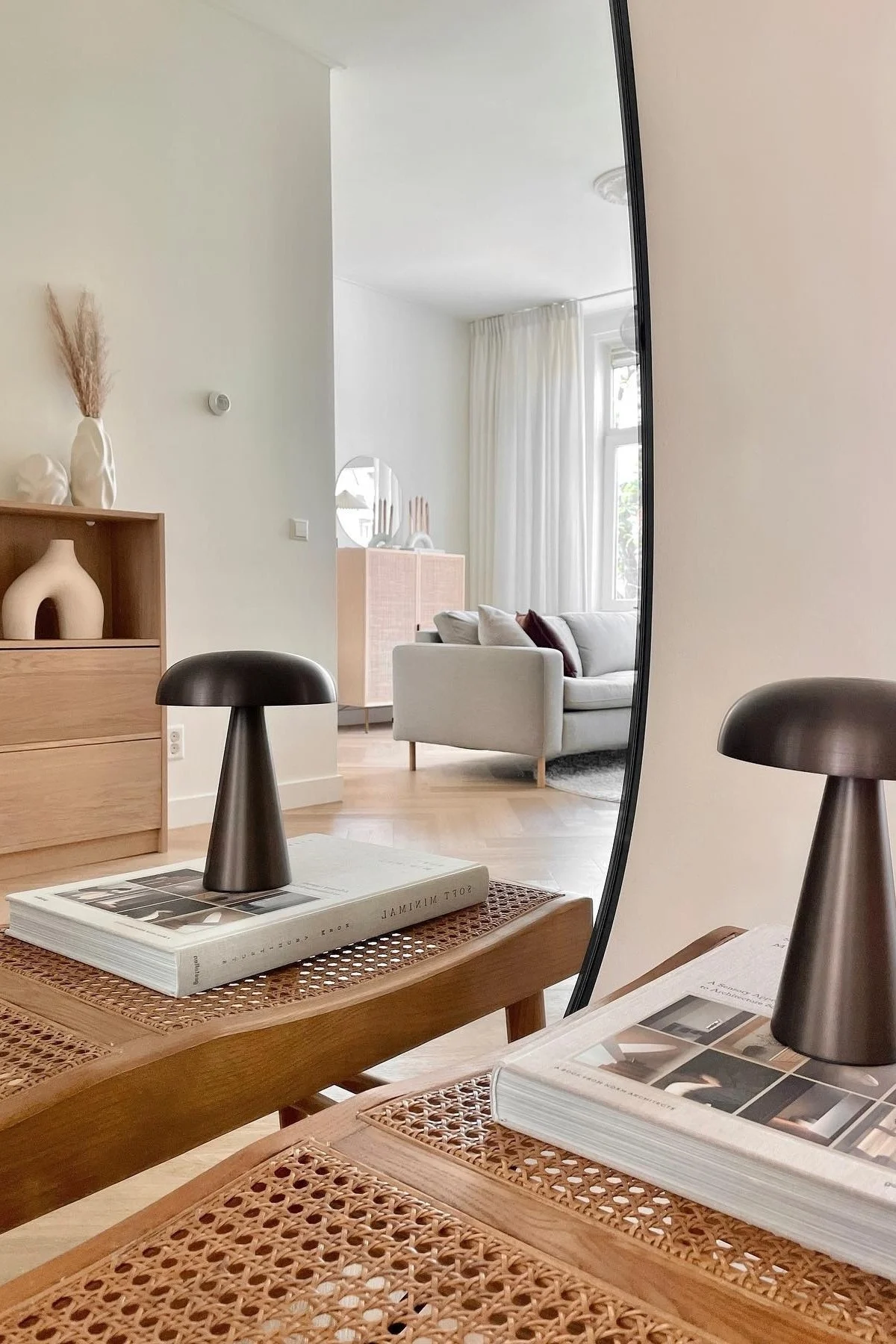 Here you see the Como portable lamp from &tradition standing on a book in a clean, uncluttered Japandi style living room.