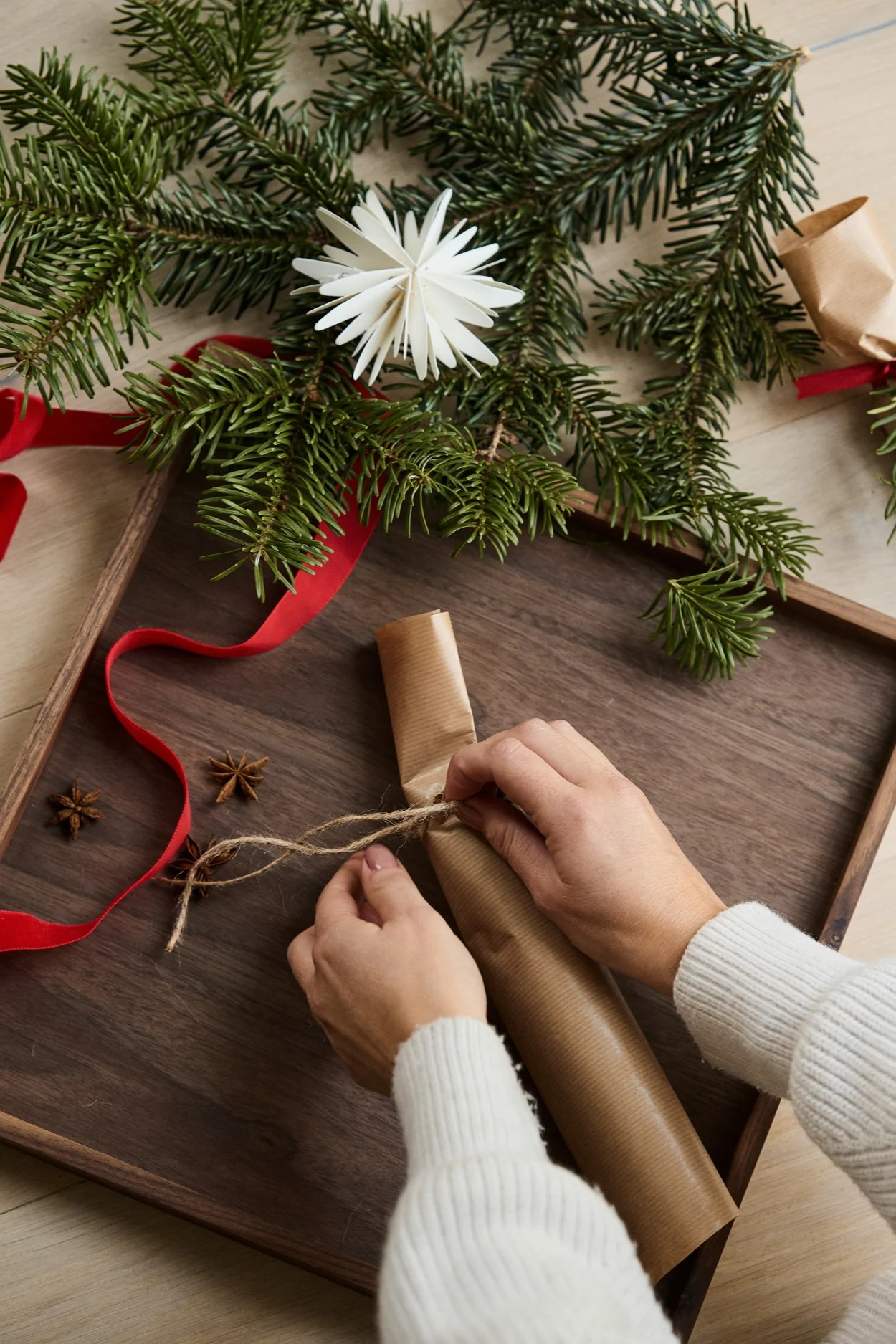 Step 3 in making your own Christmas crackers tie one end of the cracker shut.