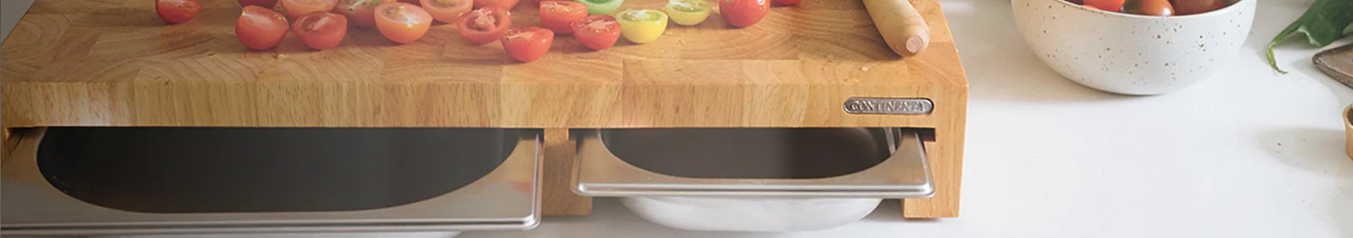 Wooden cutting board with halved colorful tomatoes, pull-out trays, and a bowl.