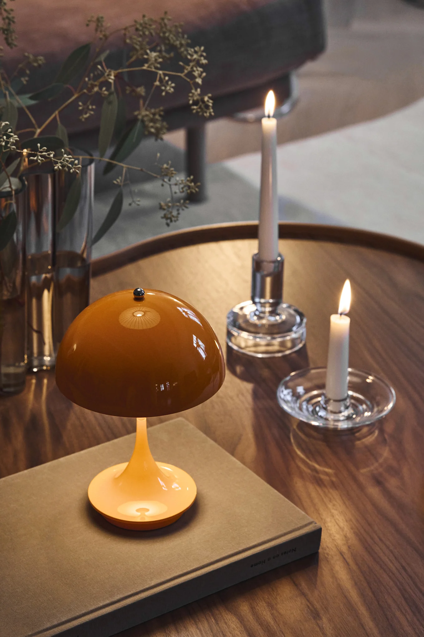 The Panthella table lamp in orange, designed by Verner Panton, stands on a coffee table.