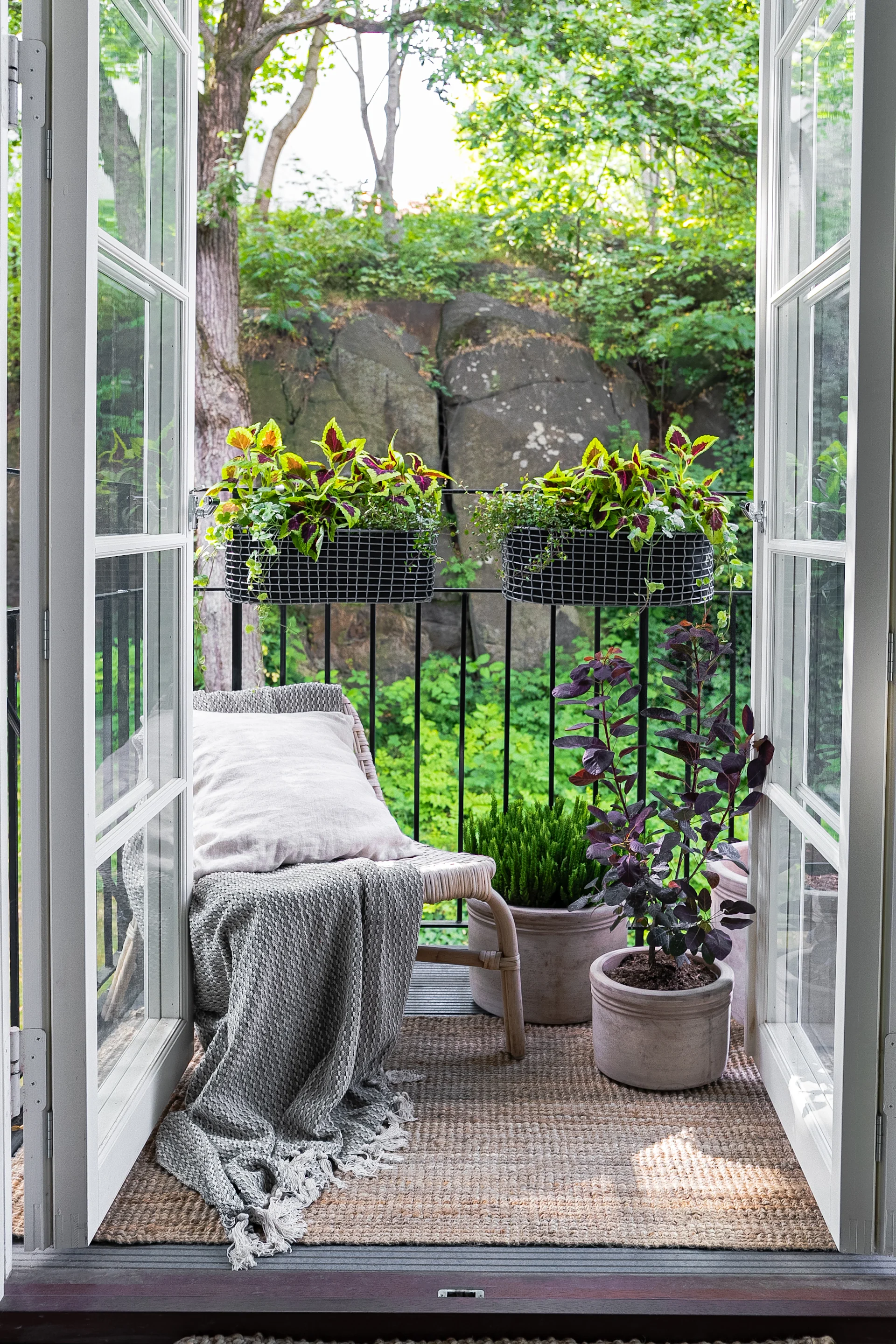 A small, cosily furnished balcony with an armchair and several plants, including in the Korbo balcony box.
