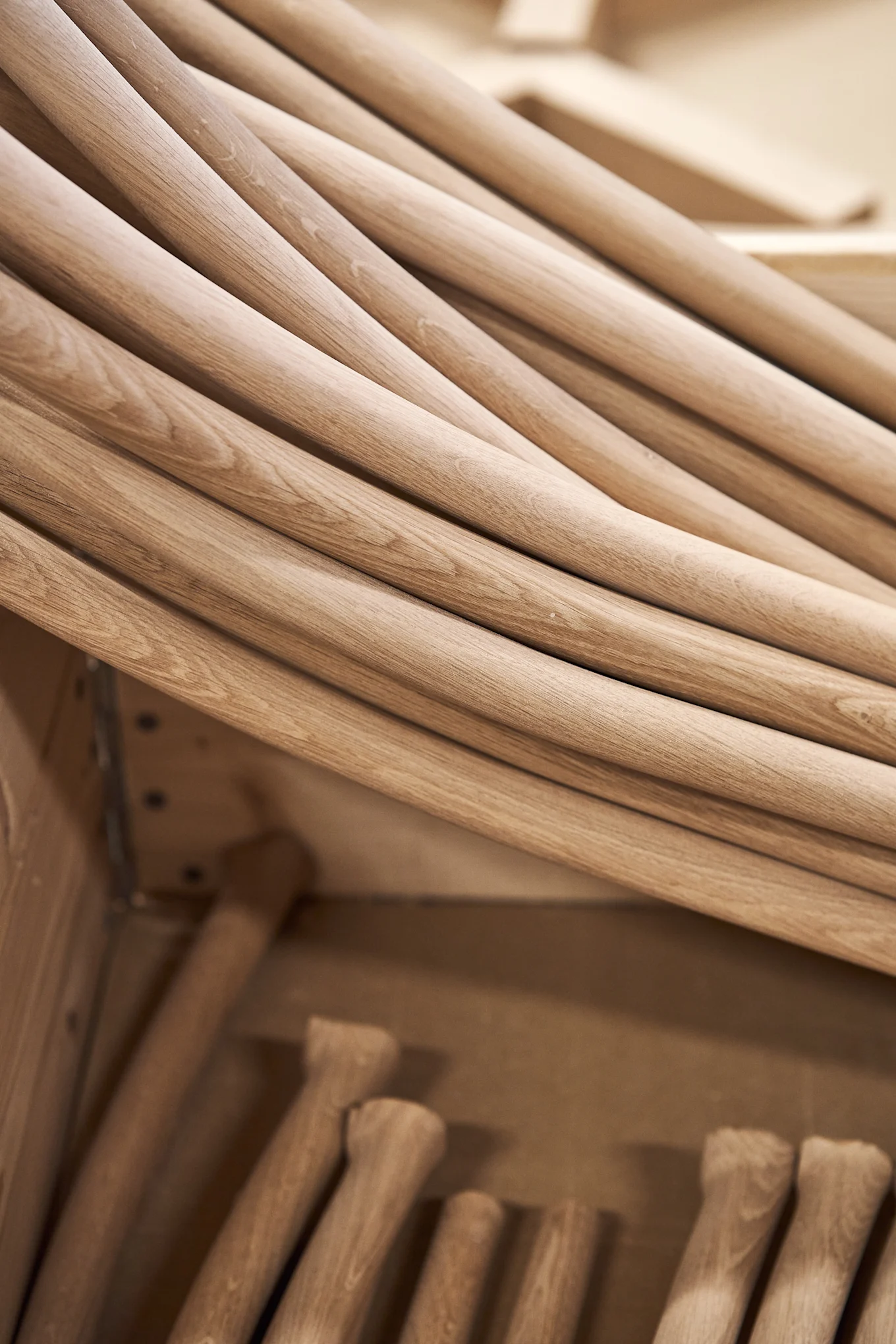 A close-up view of numerous light-colored, rounded wooden handles or dowels, stacked in storage.