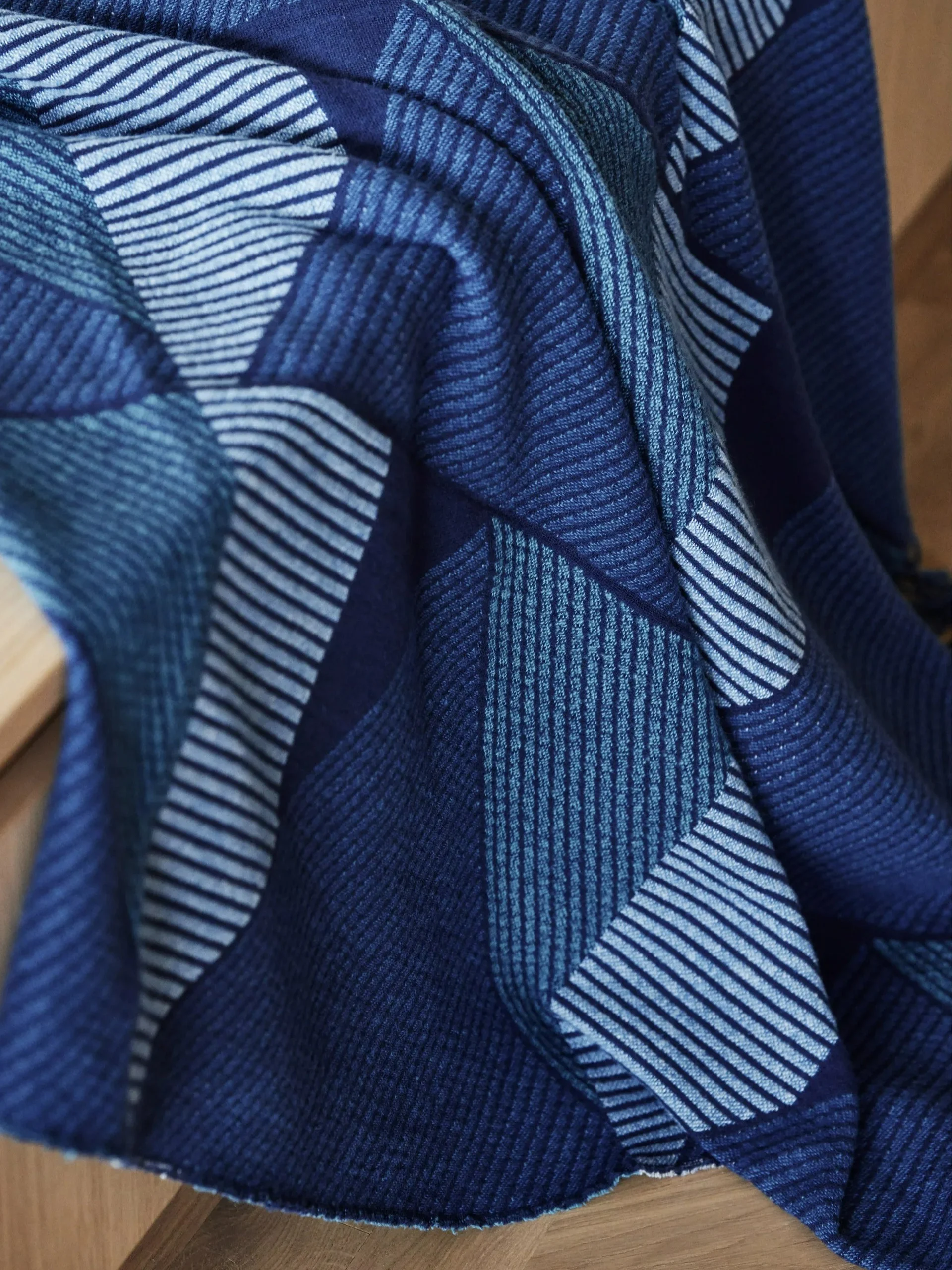 A folded blue blanket with a geometric pattern of various blue stripes and solid blocks.